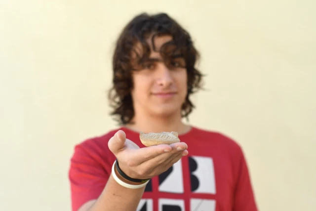 Yonatan Frankel and the lamp that he found (Photo: Yoli Schwartz, Israel Antiquities Authority).
