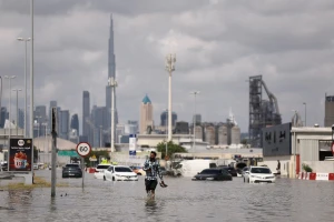 A person walks in flood water caused by heavy rains, with the Burj Khalifa tower visible in the background, in Dubai, United Arab Emirates, April 17, 2024 (Photo: REUTERS/Amr Alfiky).