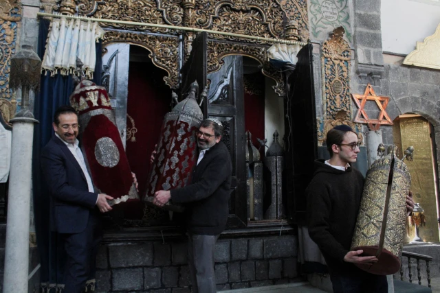 Henry Hamra and members of a Syrian Jewish delegation who are visiting Syria for the first time in decades hold a Torah Case in a Jewish synagogue in Damascus, Syria February 18, 2025. REUTERS/Firas Makdesi