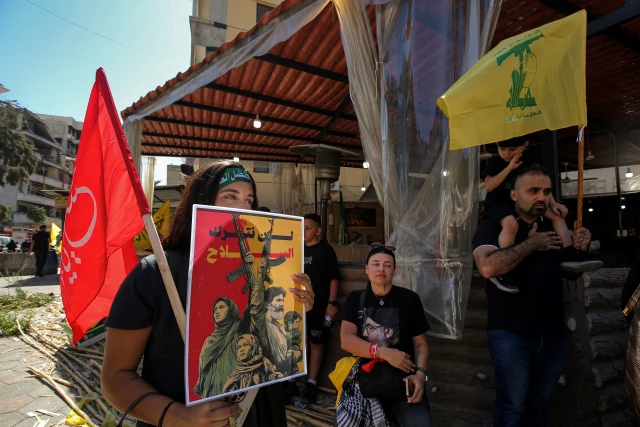 A pro-Iranian Hezbollah supporter, holding a poster that reads: "We will not abandon the weapons" attends a mass rally to mark Ashoura, commemorating the martyrdom of the Prophet Muhammad grandson Hussein. July 6, 2025, Beirut, Lebanon. Photo: ZUMA Press Wire via Reuters Connect