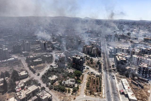 An aerial view shows the city of As Suwayda, with smoke rising from burning houses amid clashes between tribal fighters and local Druze factions in southern Syria, July 19th, 2025. Photo: Reuters by Moawia Atrash