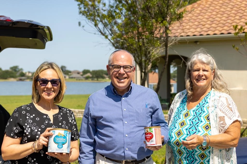 Pabliana Franco (L) of New Beginnings Church receives formula from Jonathan Feldstein and Genesis 123 Foundation board member, Rev. Linda Chandler (Photo courtesy Genesis 123 Foundation)