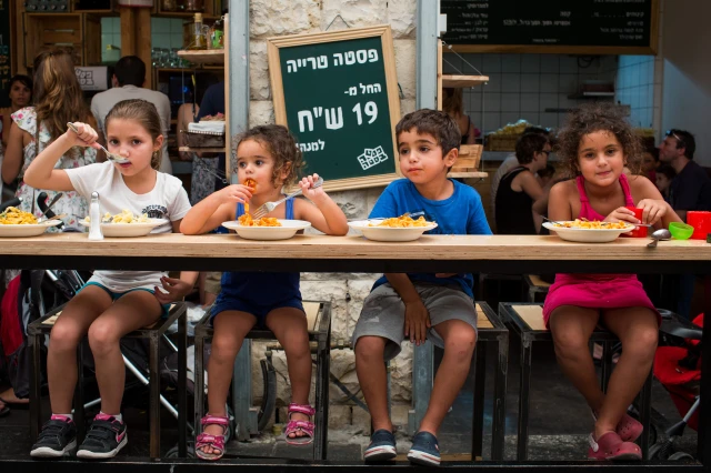 Illustrative: Young Israeli kids eat at a restaurant in the Mahane Yehuda in Jerusalem. Photo by Yonatan Sindel/Flash90