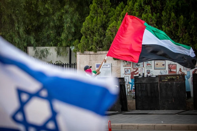 A man waves a giant United Arab Emirates flag outside the Prime Minister's official residence in Jerusalem on August 19, 2020. Photo by Yonatan Sindel/Flash90
