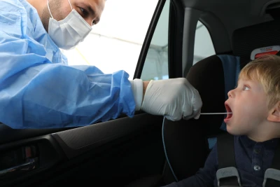 Health care workers take test samples of an Israeli kid in a drive through complex to check if he has been infected with the Covid-19, in Netanya, on April 13, 2021. Photo by Chen Leopold/Flash90