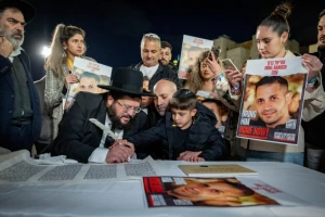The son of Uriel Baruch write the finishing letters in a new Torah Scroll dedicated to the return of the hostages and in memory of the civilians and soldiers killed in war, at the Western Wall in Jerusalem's Old City, November 21, 2023 (Photo: by Yonatan Sindel/Flash90).