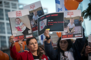 Israelis hold photographs of the Bibas family, and orange balloons, at a press conference calling for the release of 10 month old Kfir, 4 year old Ariel, and their parents Shiri and Yarden Bibas. at "Hostage Square" in Tel Aviv, November 28, 2023. Photo by Miriam Alster/Flash90