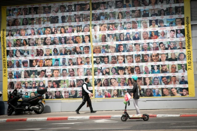 People walk by photographs of Israeli civilians held hostage by Hamas terrorists in Gaza, in Tel Aviv. April 9, 2024 (Photo: Miriam Alster/FLASH90).