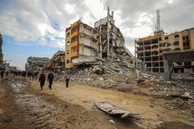 Palestinians walk next to damaged buildings after the Israeli army withdrew from the area, in the Nuseirat camp, in the central Gaza Strip, on November 29, 2024. Photo by Ali Hassan/Flash90
