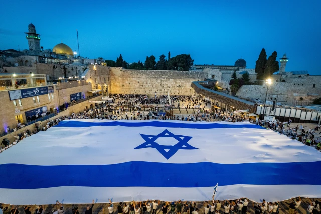People hold a giant Israeli national flag at the Western Wall in Jerusalem Old City, on the eve of Jerusalem Day, May 25, 2025. Photo by Chaim Goldberg/Flash90