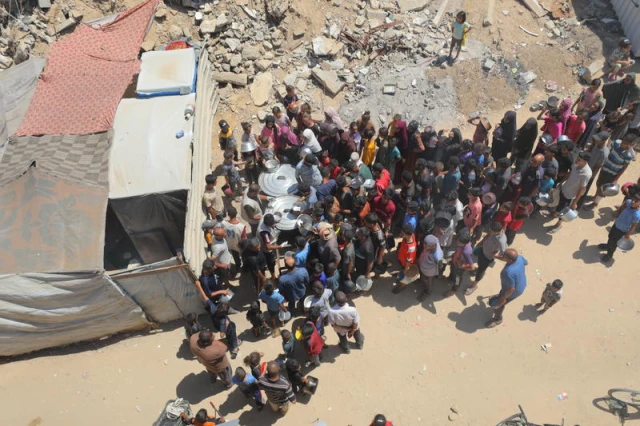 Palestinians receive meals from volunteers in Deir al-Balah, in central Gaza Strip, on July 14, 2025. Photo by Ali Hassan/Flash90