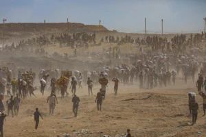 Displaced Palestinians carry food parcels and supplies from a GHF aid distribution point at the “Netzarim corridor” in the central Gaza, August 5, 2025. Photo by Ali Hassan/Flash90