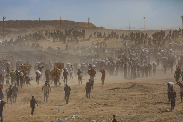 Displaced Palestinians carry food parcels and supplies from a GHF aid distribution point at the “Netzarim corridor” in the central Gaza, August 5, 2025. Photo by Ali Hassan/Flash90