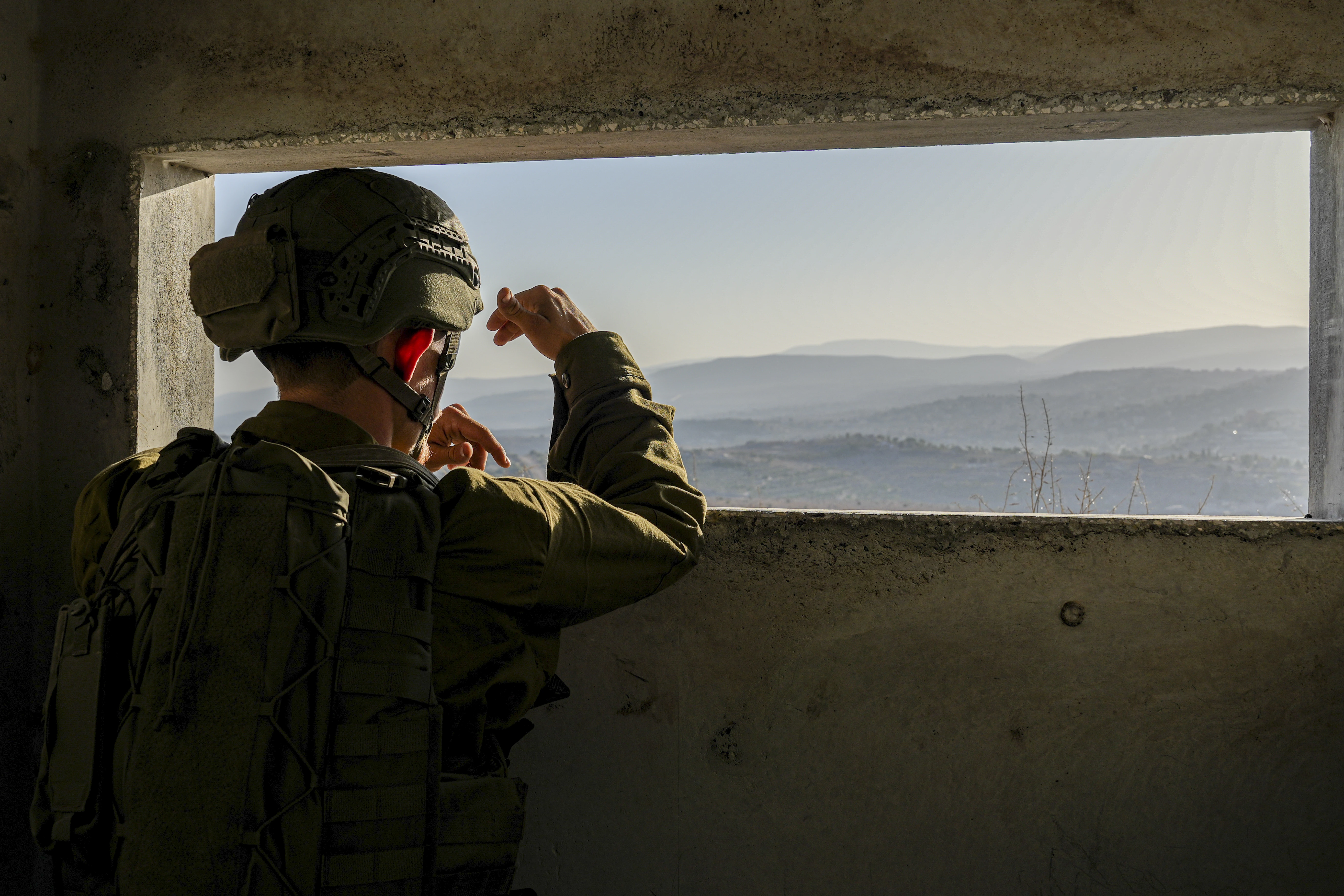 An Israeli soldier looks on as smoke rises in southern Lebanon following an Israeli airstrike, seen from the Israeli side of the border, November 22, 2025. Photo by Ayal Margolin/Flash90