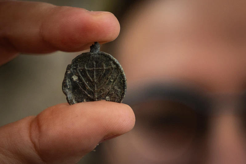 An Israeli Antiquities Authority (IAA) archaeologist holds a a 1,300-year-old menorah-decorated pendant discovered during an Israel Antiquities Authority archaeological excavation near the Western Wall in Jerusalem’s Old City, December 15, 2025. Photo by Yonatan Sindel/Flash90