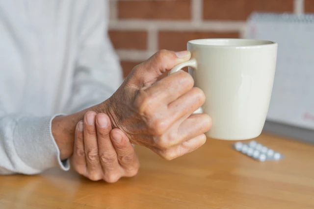 Illustration: Close-up of an elderly woman steadying her hand while drinking, illustrating symptoms associated with Parkinson’s disease.
Photo: Shutterstock