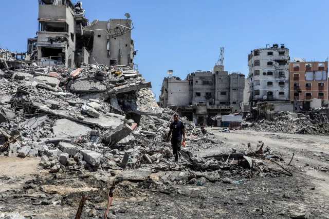 Palestinians walk next to destroyed buildings and pools with stagnant water in Khan Yunis, in the southern Gaza Strip, on July 19, 2024. Photo: Shutterstock