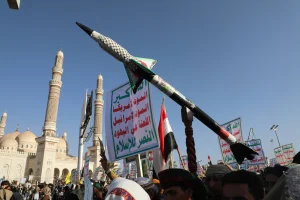 A Houthi supporter carries a mock Houthi-made missile during a mass Protest against Israeli airstrikes on Yemen. The sign shows the Houthis' slogan demanding: "Death for America, death for Israel, a curse upon the Jews." Sana'a, Yemen, 20 December 2024. IMAGO/Hamza Ali via Reuters Connect