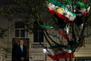Demonstrators stand on tree branches displaying "Lion and Sun" pre-Iranian Revolution national flags outside the Iranian embassy during a rally in support of nationwide protests in Iran, in London, Britain, January 11, 2026. Photo: Reuters Connect by Isabel Infantes
