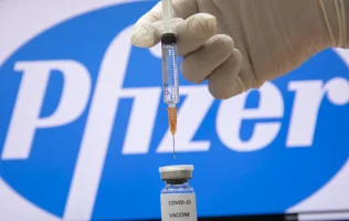 A photo illustration of a syringe and and a bottle reading "Covid-19 Vaccine" next to the Pfizer company logo in Jerusalem on December 10, 2020. Photo by Olivier Fitoussi/Flash90