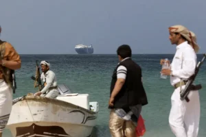 Armed men stand on the beach as the Galaxy Leader commercial ship, seized by Yemen's Houthis, is anchored off the coast of al-Salif, Yemen, Dec. 5, 2023. (Photo: REUTERS/Khaled Abdullah/File Photo)