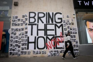 People walk by photographs of civilians held hostage by Hamas terrorists in Gaza, posted in Tel Aviv. December 21, 2023 (Photo: Miriam Alster/FLASH90).
