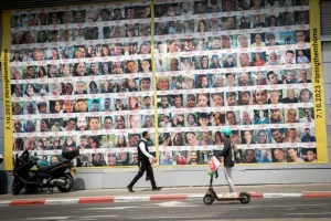 People walk by photographs of Israeli civilians held hostage by Hamas terrorists in Gaza, in Tel Aviv. April 9, 2024 (Photo: Miriam Alster/FLASH90).
