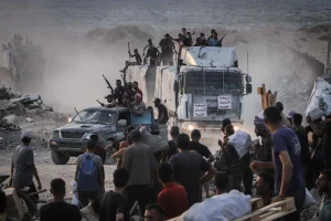 Armed Palestinians sit on trucks carrying humanitarian aid near the Zikim border crossing between Israel and Beit Lahia in the northern Gaza Strip, August 18, 2025. Photo by Khalil Kahlout/ Flash90