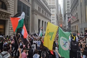 A Palestinian flag, a yellow-and-green flag of the Hezbollah terrorist group, and a terrorist group green flag waved over Manhattan during an anti-Israel rally. 2024 (Photo: Screenshot).