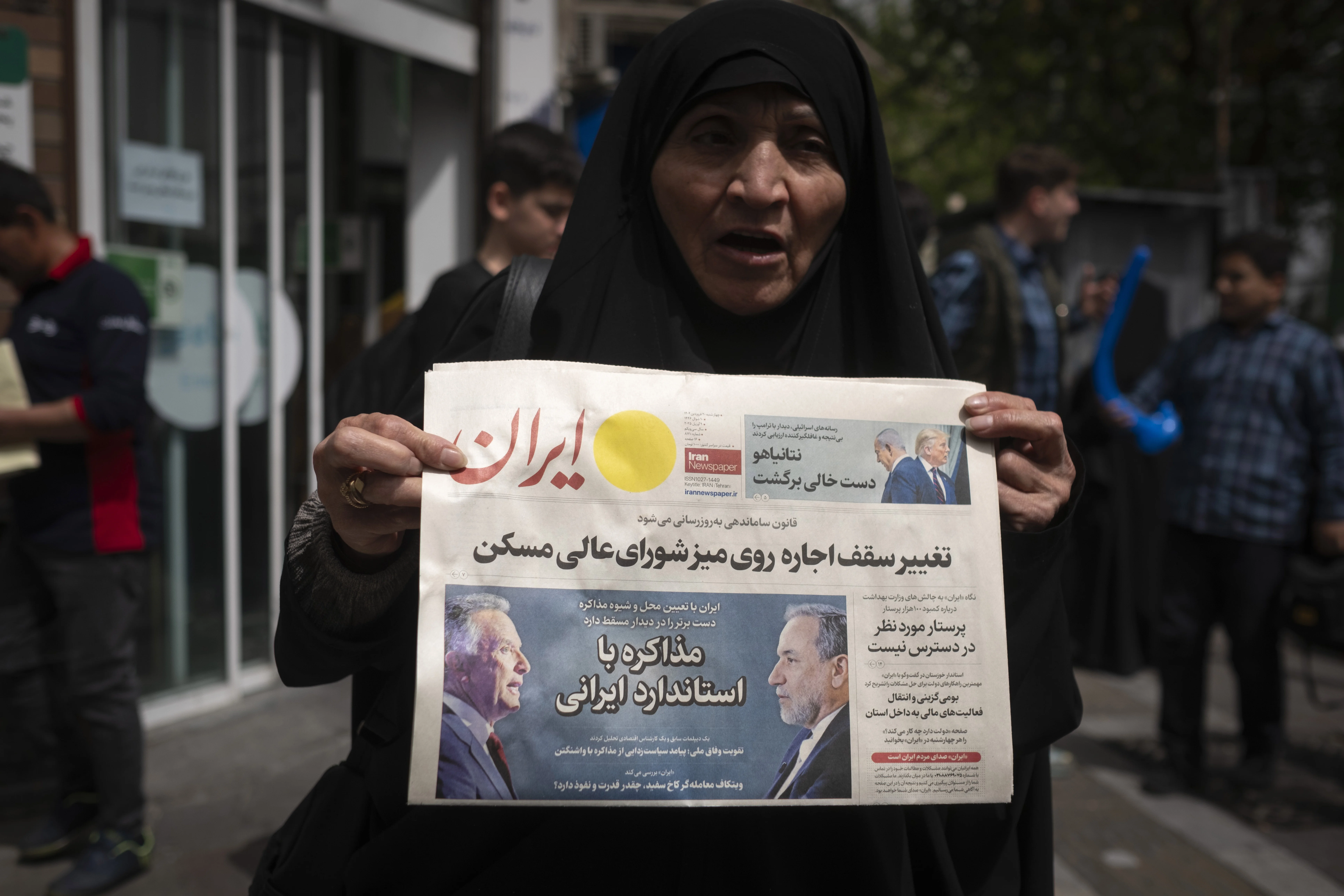A veiled Iranian woman holds a newspaper featuring portraits of Iranian Foreign Minister Abbas Araghchi and Steve Witkoff, White House special envoy, while she shows her protest against Iran and U.S. negotiations in downtown Tehran, Iran, on April 9, 2025. Photo via Reuters.