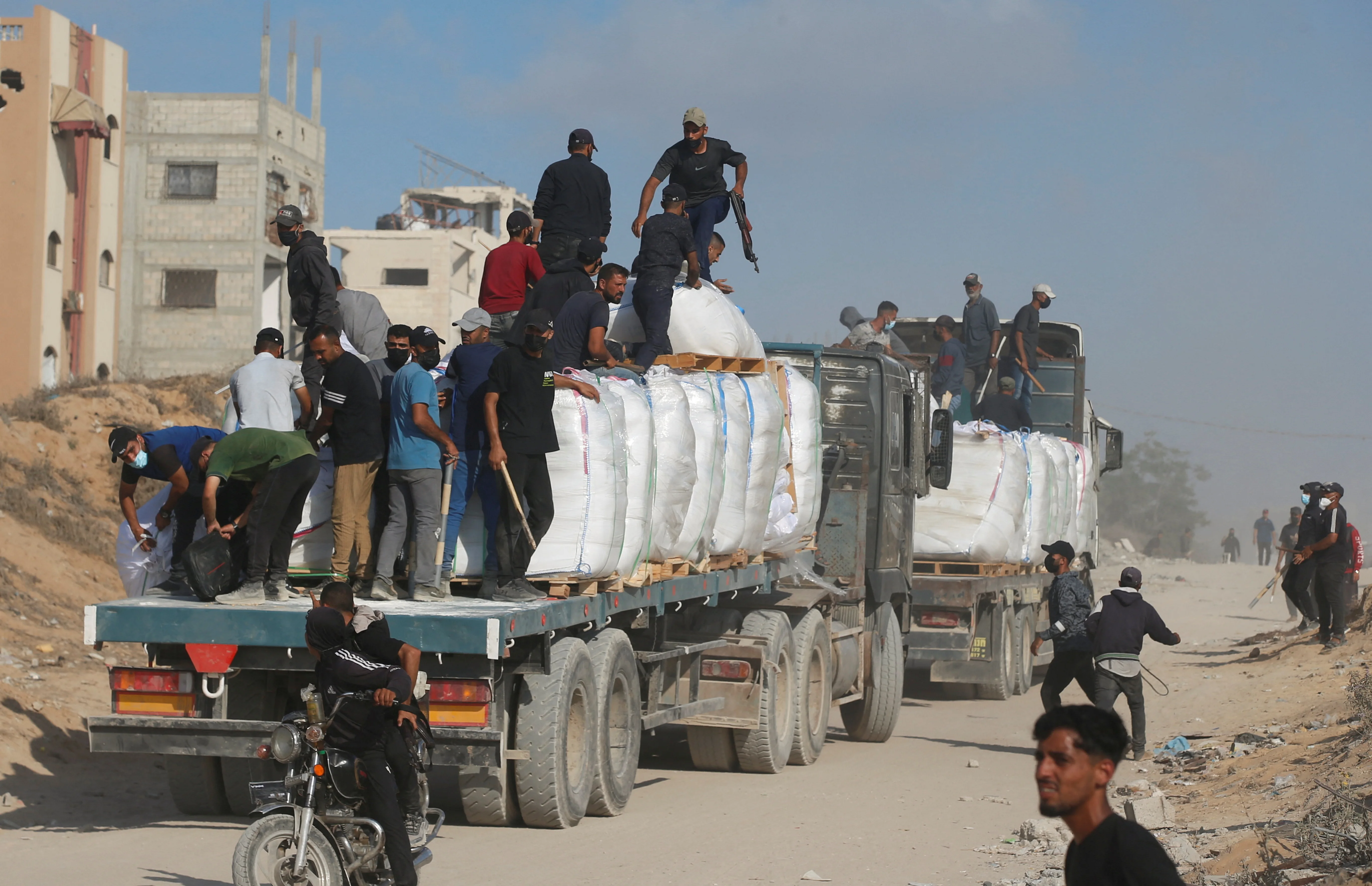 Palestinians from clans hold guns and melee weapons to secure aid trucks in Beit Lahia, in the northern Gaza Strip, June 25, 2025. REUTERS/Mahmoud Issa