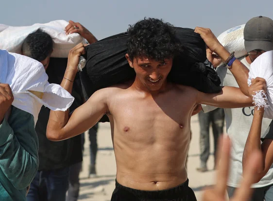 Palestinians carry aid supplies that entered Gaza through Israel, in Beit Lahia, northern Gaza Strip, August 2, 2025. REUTERS/Mahmoud Issa