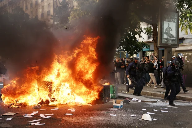 French CRS riot police run past garbage bins and object set on fire amid clashes with protesters during a demonstration as part of a nationwide day of protests and blockades, France, October 6, 2026. (Photo: REUTERS/Abdul Saboor)