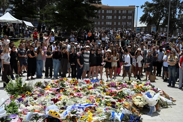 People react in front of a flower tribute near Bondi Pavilion following a shooting incident at Bondi Beach in Sydney, Australia, December 15, 2025. (Photo: REUTERS/Flavio Brancaleone)
