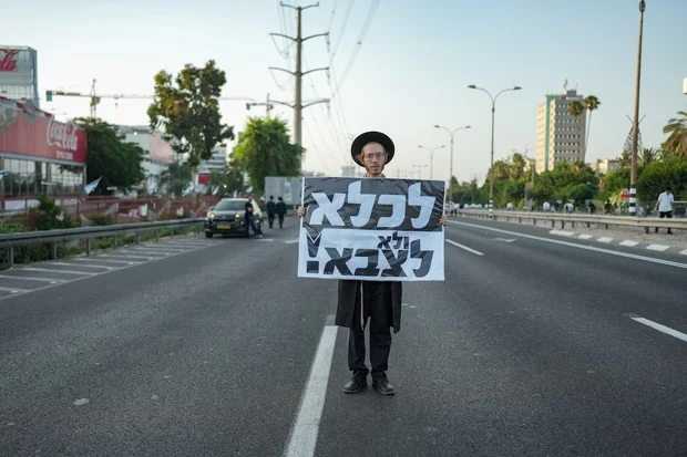 An ultra-Orthodox protester holds a sign that reads, 