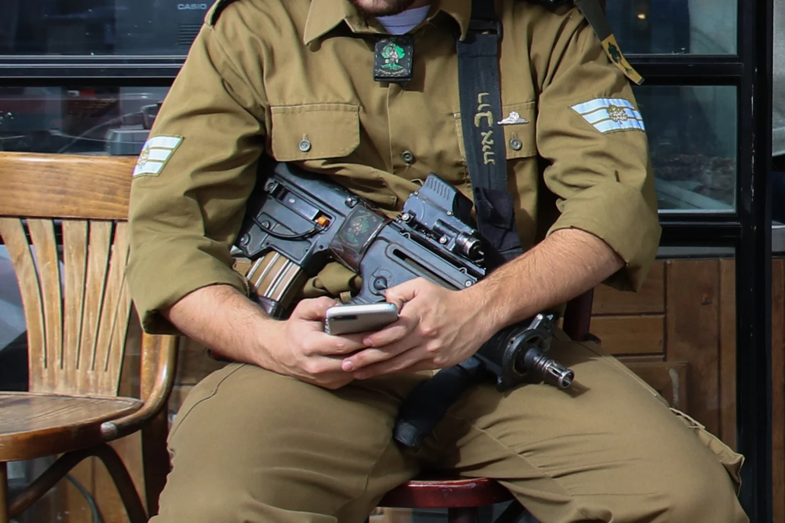 An IDF soldier sitting with his phone in front of a restaurant on Agripas street, on February 12, 2018. Photo by Liba Farkash/Flash90