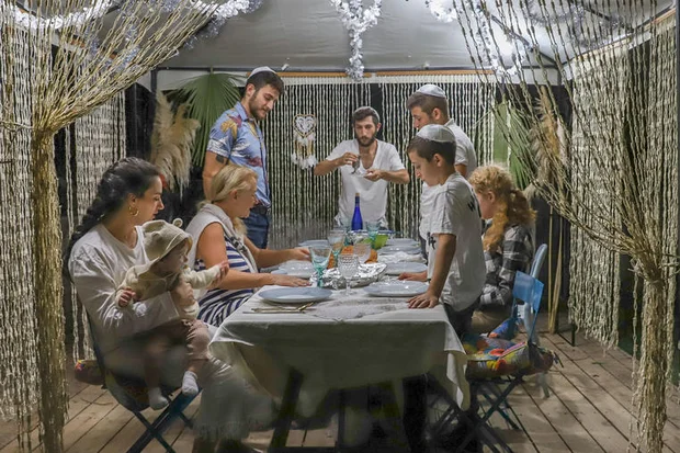 A Jewish family sitting in a Sukkah during the Jewish holiday of Sukkot, in Moshav Yashresh, on October 2, 2020. Photo by Yossi Aloni/Flash90