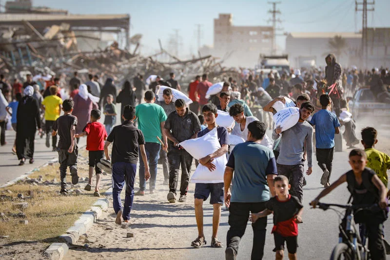 Palestinians carrying bags of flour outside distribution point controlled by the 'Gaza Humanitarian Relief Foundation' in Deir al-Balah, in the Gaza Strip, May 28, 2025. Photo by Ali Hassan/Flash90