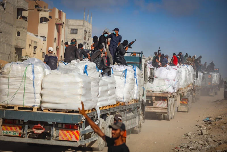 Armed Palestinians sit on trucks carrying humanitarian aid near the Zikim border crossing between Israel and Beit Lahia in the northern Gaza Strip, June 25, 2025. Photo by Ali Qariqa/Flash90