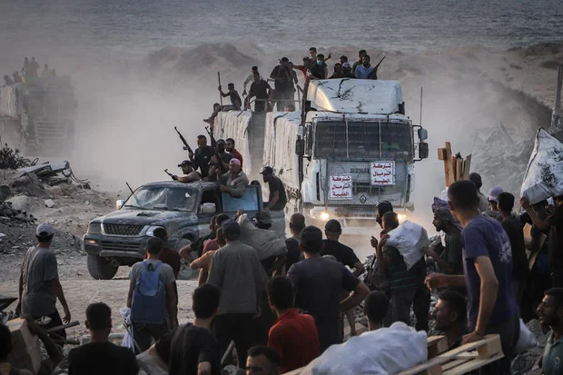 Armed Palestinians sit on trucks carrying humanitarian aid near the Zikim border crossing between Israel and Beit Lahia in the northern Gaza Strip, August 18, 2025. Photo by Khalil Kahlout/ Flash90