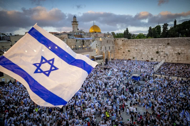 Jews hold Israeli flags as they dance at the Western Wall in Jerusalem's Old City