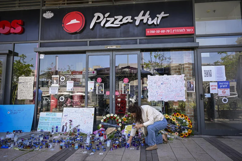 People gather outside a Pizza Hut branch in Petah Tikva, lighting candles and placing flowers in memory of employee Yemanu Binyamin Zalka, who was stabbed and later died of his wounds on the eve of Independence Day, April 27, 2026. Photo by Avshalom Sassoni/Flash90