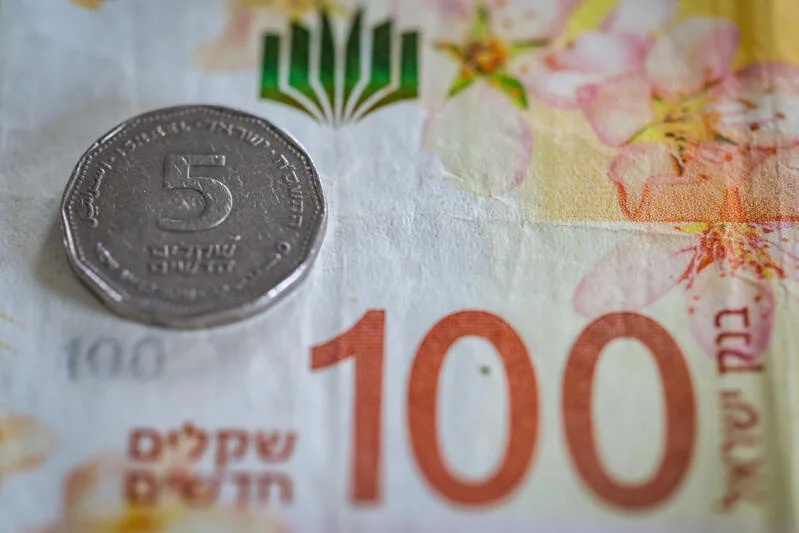 Five shekel coin placed on a 100 shekel banknote,