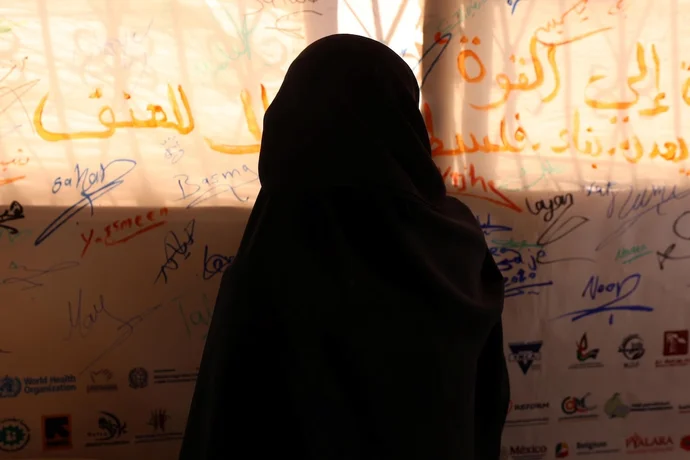 A Gazan woman looks at a wall of collective voices calling for dignity and an end to violence