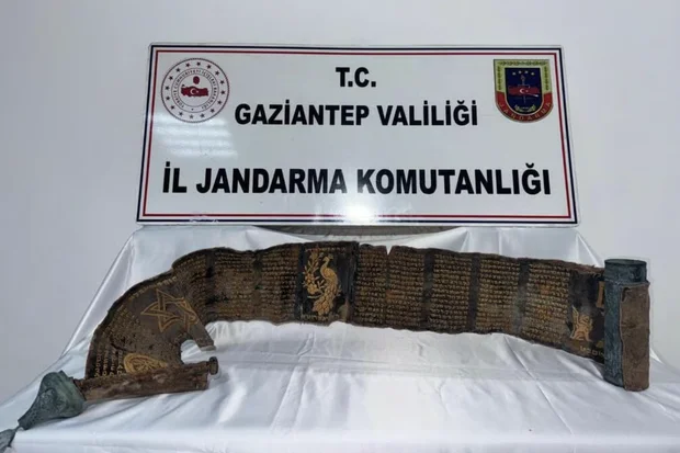 The Hebrew manuscript inscribed in gold letters on python skin, displayed alongside its decorated copper case (Photo: AA)